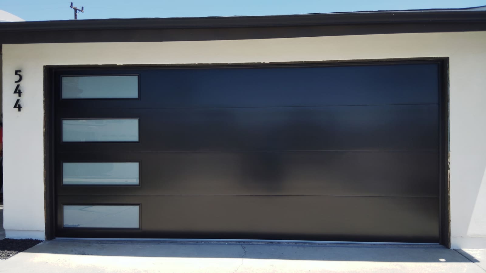 Smooth black modern steel garage door with stacked windows